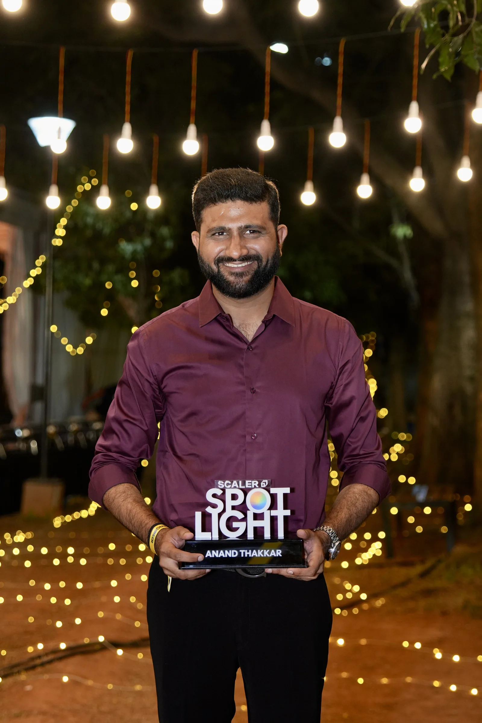 Anand Thakkar holding the Scaler Spotlight trophy engraved with his name at an evening event in Bangalore, 5th September 2026